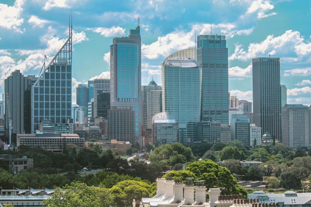 Aerial view of Sydney's iconic skyline featuring modern skyscrapers under a blue sky with clouds.